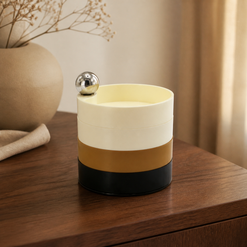 Boîte de rangement rotative multicolore ivoire ocre doré et noir sur une console en noyer