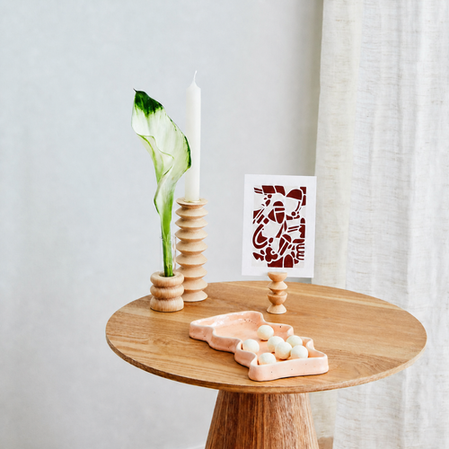 Vide-poche ondes en céramique pêche mouchetée avec éléments décoratifs blancs, centré sur une table en bois